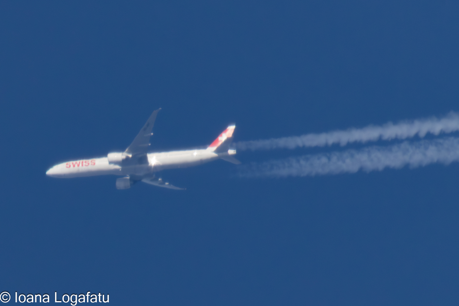 Jet streaks across a clear blue sky above